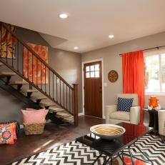 Taupe Living Room With Orange Drapes and Chevron Rug