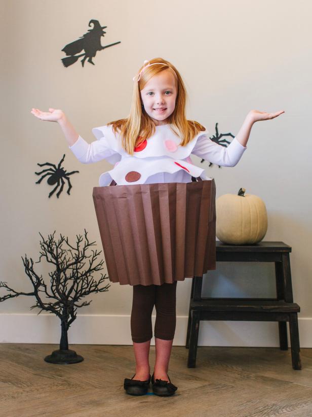 First have the child put on leggings and a white shirt. Then secure the cupcake wrapper by tying the ribbon at the shoulders, followed by the felt frosting pieces. Use safety pins as needed to secure the costume.