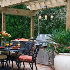 Outdoor Kitchen and Dining Area With Rustic Wood Pergola