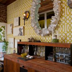 Country-Style Bar With Yellow Trellis Wallpaper and Round Mirror 