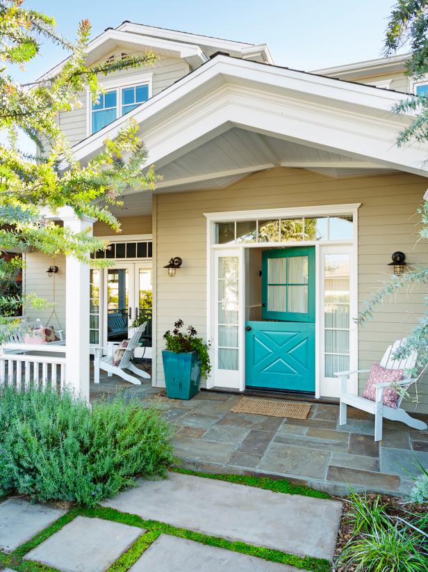 This lovely home exterior features precise landscaping and a teal horse barn front door