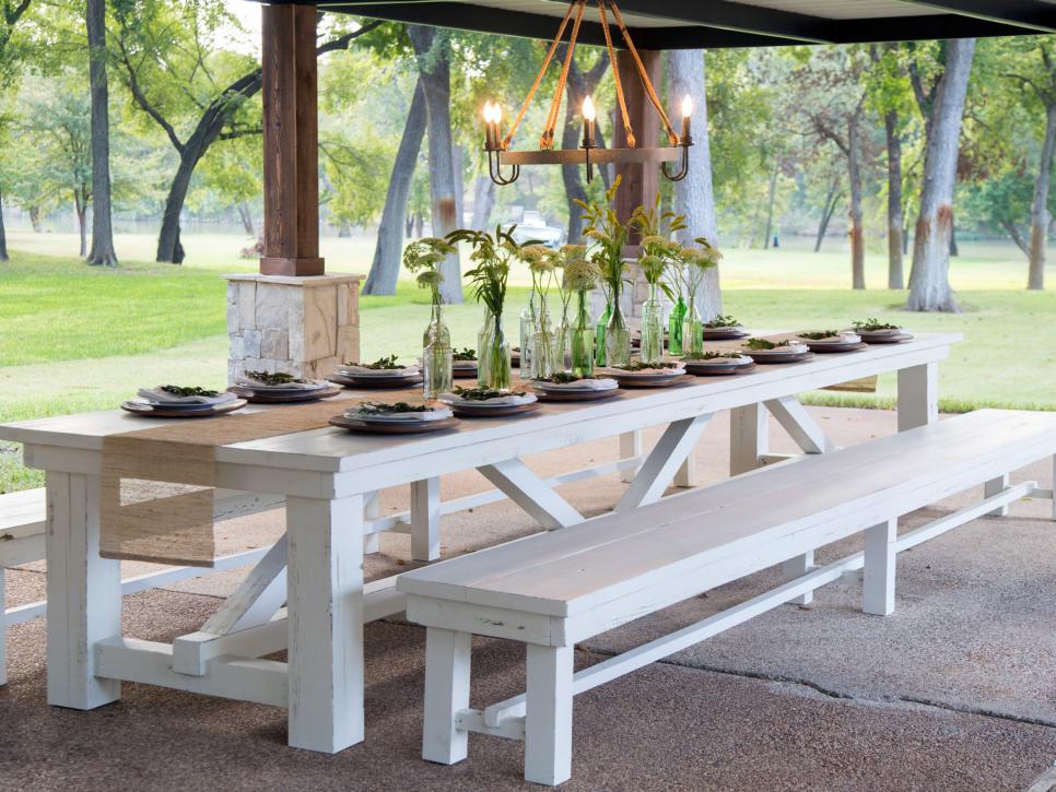 Long farm table and benches painted white in a covered patio on Fixer Upper. Come find out the answer to: What Home Improvement Shows are Most Popular in the USA?