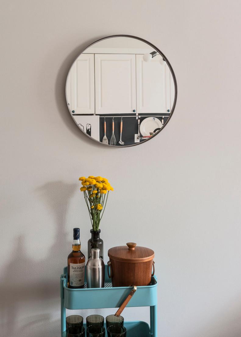 Round Mirror Above Teal Cart With Bar Accessories