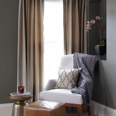 Stylish Sitting Area With Neutral Arm Chair Draped With A Chevron Throw and Patterned Pillow With Leather Cube Ottoman 