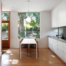 Sunny, Modern Eat In Kitchen White Dining Table Under Large Window, White Laminate Cabinets and Wood Dining Chairs