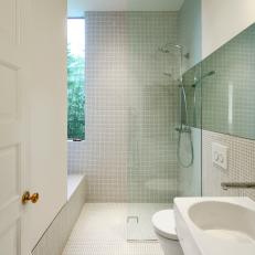 Modern Bathroom With Small White Tile, Glass Wall Shower Divider and Floating White Sink and Toilet 
