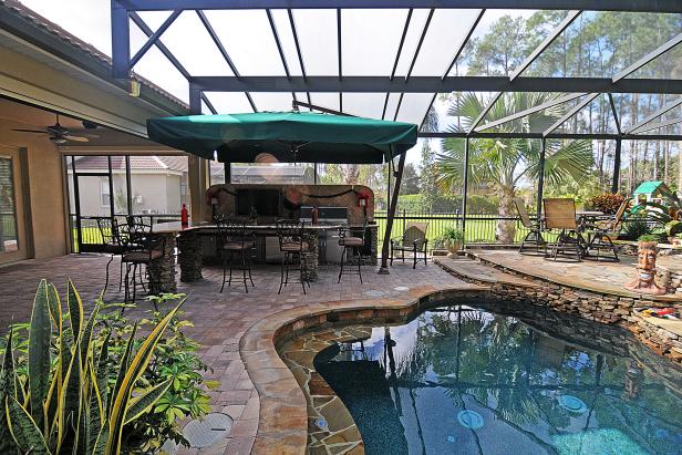 A Screened In Patio With An Outdoor Kitchen And Rock Tile Pool - Screened In Patio With Outdoor Kitchen