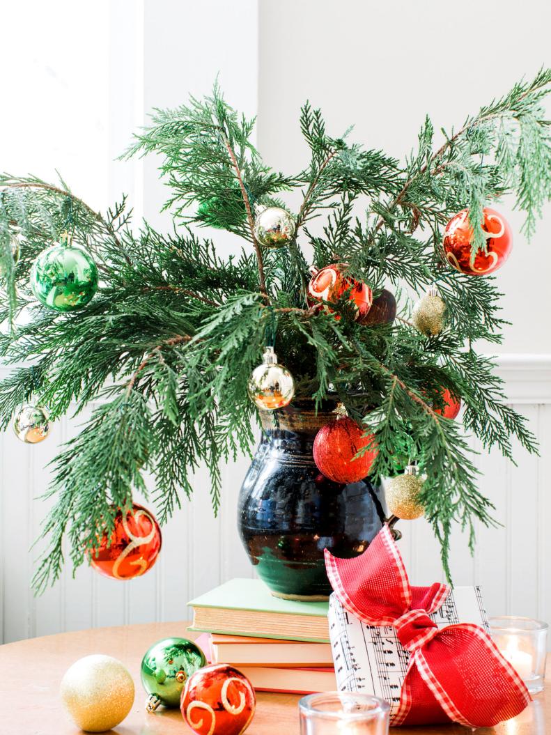 Put tabletop surfaces to good use by snipping greenery from live exterior trees, adding them into large vessels and placing them in the center. Next, use the space below the cuttings to arrange gifts as an alternative to a true Christmas tree.