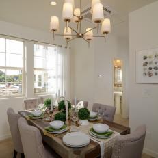 Transitional Dining Room With Full, Decorative Table Setting and Centerpiece, Tufted Neutral Chairs and Contemporary Chandelier