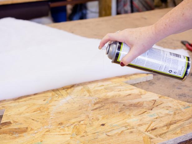 Spray adhesive onto the boardâs surface  then roll out batting on top. Press into place, then trim neatly along the edges . To ensure batting stays put, staple once on each corner Repeat on either side of each board.