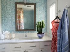 Crisp white surfaces mixed with a variety of blue penny tile and a custom coral reef shower curtain give this guest bathroom a sophisticated finish.