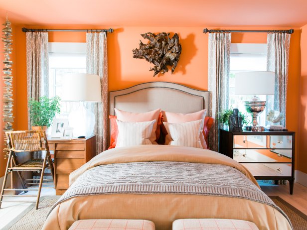 The comfortable and stylish first-floor guest bedroom with terra cotta walls and ceiling includes coral accents and subtle shore-inspired elements like driftwood garland for a chic coastal look.