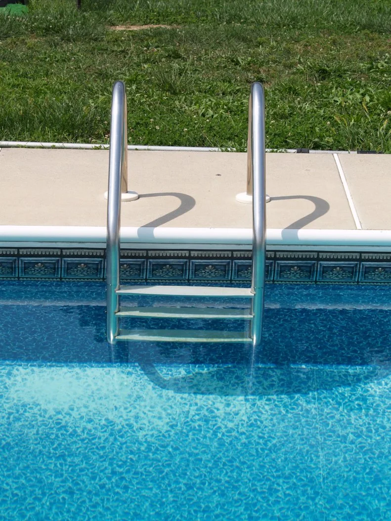 Pool ladder and ornamental tile around in-ground pool