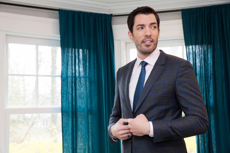 Host Drew Scott poses for a portrait in the living room of Angela and Ro's new home. The room has jewel-toned accessories and bright yellow chairs, which set off the neutral paint and couch colors, as seen on Property Brothers. (Portrait)