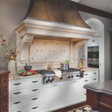Traditional Kitchen With White Cabinets and Dramatic Range Hood
