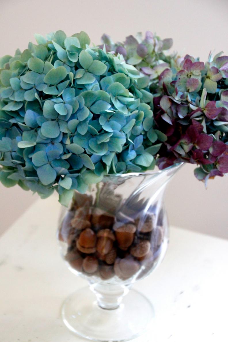 Acorns help hold dried hydrangeas in place in their vase.
