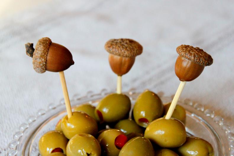 Acorns top appetizer sticks in a dish of olives.