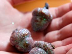 To make these glitter acorns, simply use a paint brush and coat them with mod podge. Then roll them in glitter and allow them to dry.