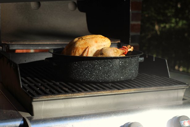 Turkey cookibng in roasting pan on an outdoor grill