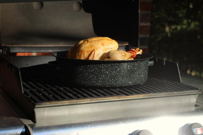 Turkey cookibng in roasting pan on an outdoor grill