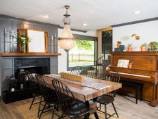 The dining room in the newly renovated Jones home was at the front of the home with the living room in its place, but a wall was removed between the living room and dining room creating an open concept. Some key elements are the restored fireplace, piano, dining table, and chandelier, as seen on Fixer Upper. (after)