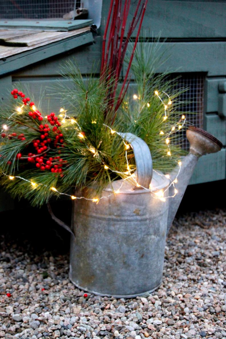 To make this wintry watering can, add a couple of inches of water to the watering can, tuck in assorted greenery and top it with outdoor lights.