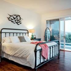 Spacious Country Bedroom With Subtle Cream Patterned Bed Comforter, Hardwood Floor and Black Metal Bed Frame 