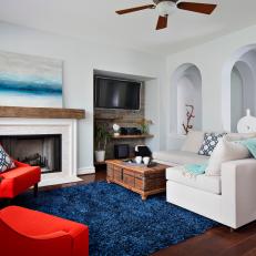 Bright, Eclectic Living Room With Blue Shag Rug, Vibrant Red Armchairs and Wood Decorative Details 