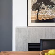 Close Up On Clean, Modern Lines of Gray Granite Fireplace Surround, Wood Dining Table and Black Leather Chair 
