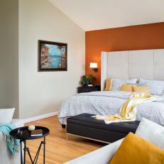 Bold Orange Accent Wall in Transitional Bedroom With Tufted Neutral Headboard and Yellow Accents 