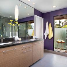 Sunny Modern Indoor/Outdoor Bathroom With Bright Purple Accent Wall, Woodgrain Cabinets and Glass Doors
