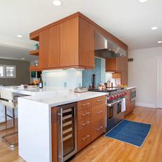 Large, Open Midcentury Modern Kitchen With Woodgrain Cabinets, Sleek White Countertop and Hardwood Floor