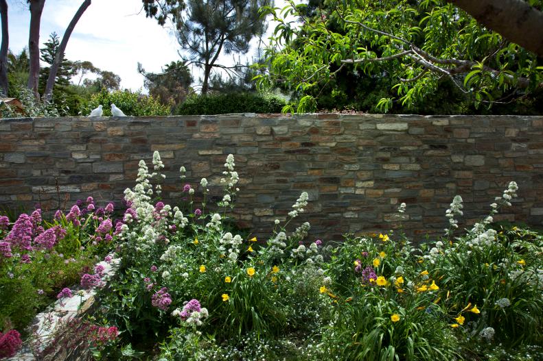 A bed of wildflowers set before a colored stone wall