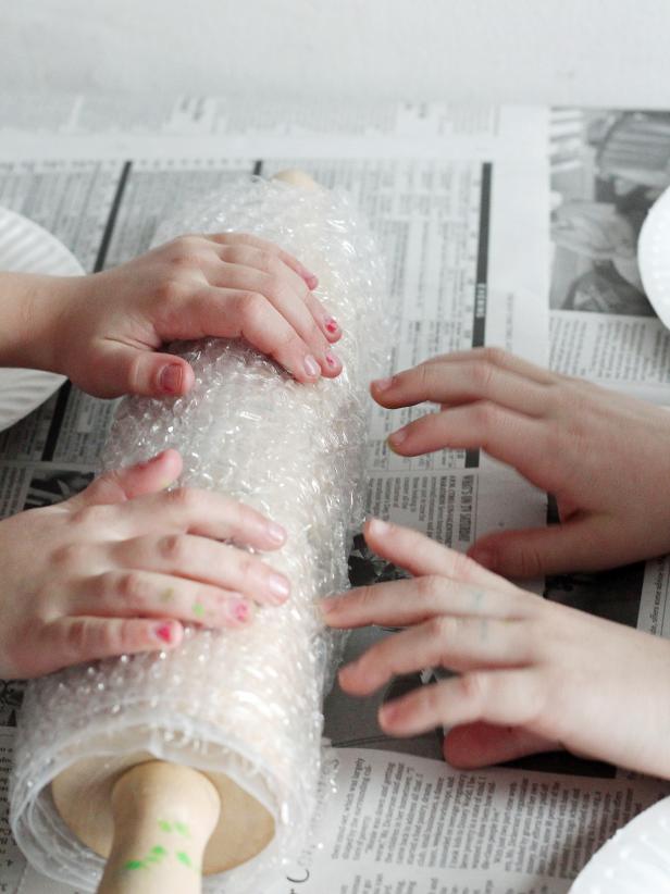 kid attaching bubble wrap to a rolling pin