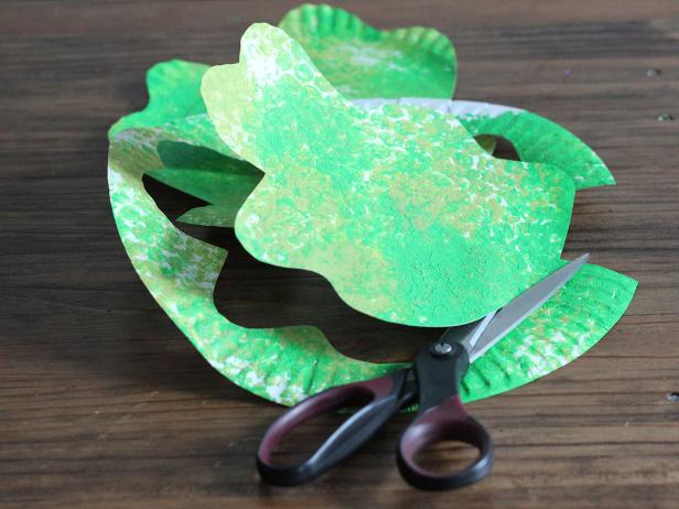 painted paper plate being cut into shamrock shape