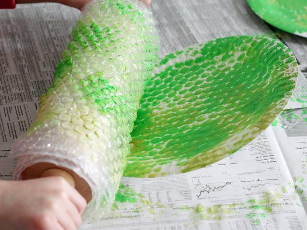 rolling bubble wrap on paper plate filled with green paint