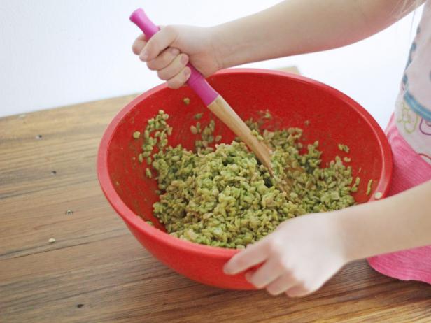 Stir ingredients to make spinach-dyed Rice Krispies treats with your kids this St. Patrick's Day.