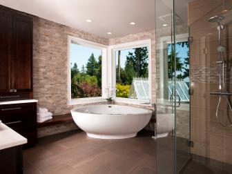 Neutral Stone Bathroom With Brown Tile Floor and Freestanding Tub