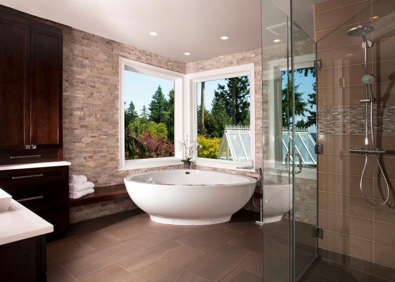 Neutral Stone Bathroom With Brown Tile Floor and Freestanding Tub