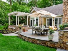 A family wanted a backyard retreat that embraced its lush natural setting. Beechwood Landscape Architecture and Construction designed a Spanish-influenced patio that makes outdoor entertaining a breeze thanks to a built-in cook station, covered dining table, sitting area with a fire pit and lounge chairs.