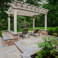 Stone Patio With Lounge Chairs Under Wood Pergola 