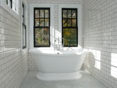 Freestanding Tub in Bathroom With White Subway Tile and Black Windows