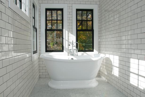 Freestanding Tub in Bathroom With White Subway Tile and Black Windows