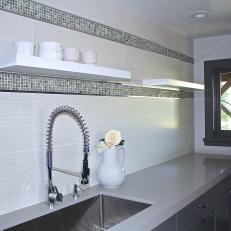 Sink and Gray Countertop With Tile Wall