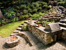 Outdoor Grill in Backyard with Waterfall and Stone Fire Pit