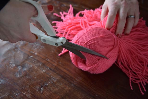 Once both ends of the skein are cut, the cinching strand will keep the skein intact while the yarn will become loose and shaggy. Use the scissors to cut each end of the skein.