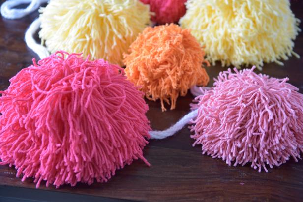 Bring texture, shape and color to your next event in a larger-than-life way with giant pom-pom garland made from yarn.