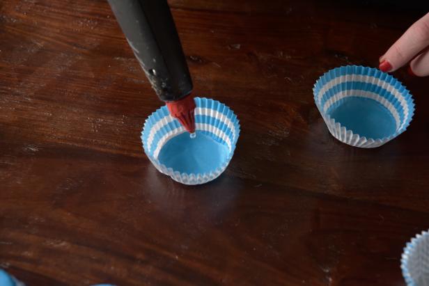 In order to make a floral shape with the cupcake liners, youâll need to layer them two deep, with one directly on top of the other. After separating the liners into different colors and patterns, add a bead of hot glue into one liner and keep the second liner nearby.