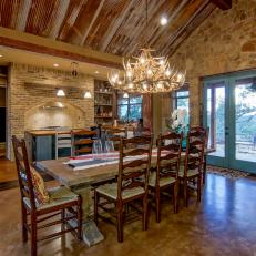 Open, Rustic Dining Room With Natural Rock Wall, High Wood Ceiling and Antler Chandelier 