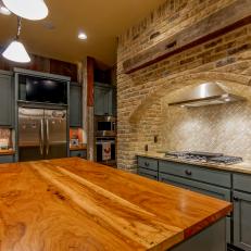Country Kitchen With Polished Wood Island, Arched Brick Stove Surround and Matte Blue Cabinets 